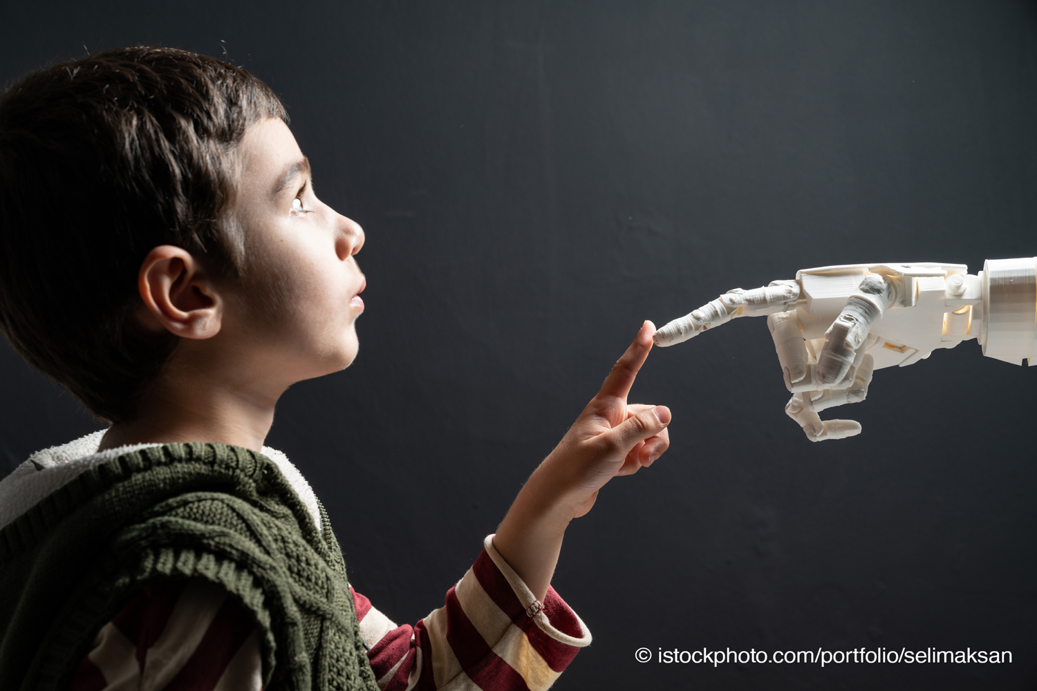 Ein Kinde berührt eine Roboterhand